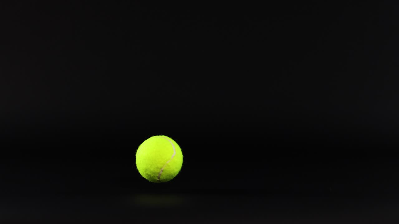 Tennis ball bouncing against a dark background