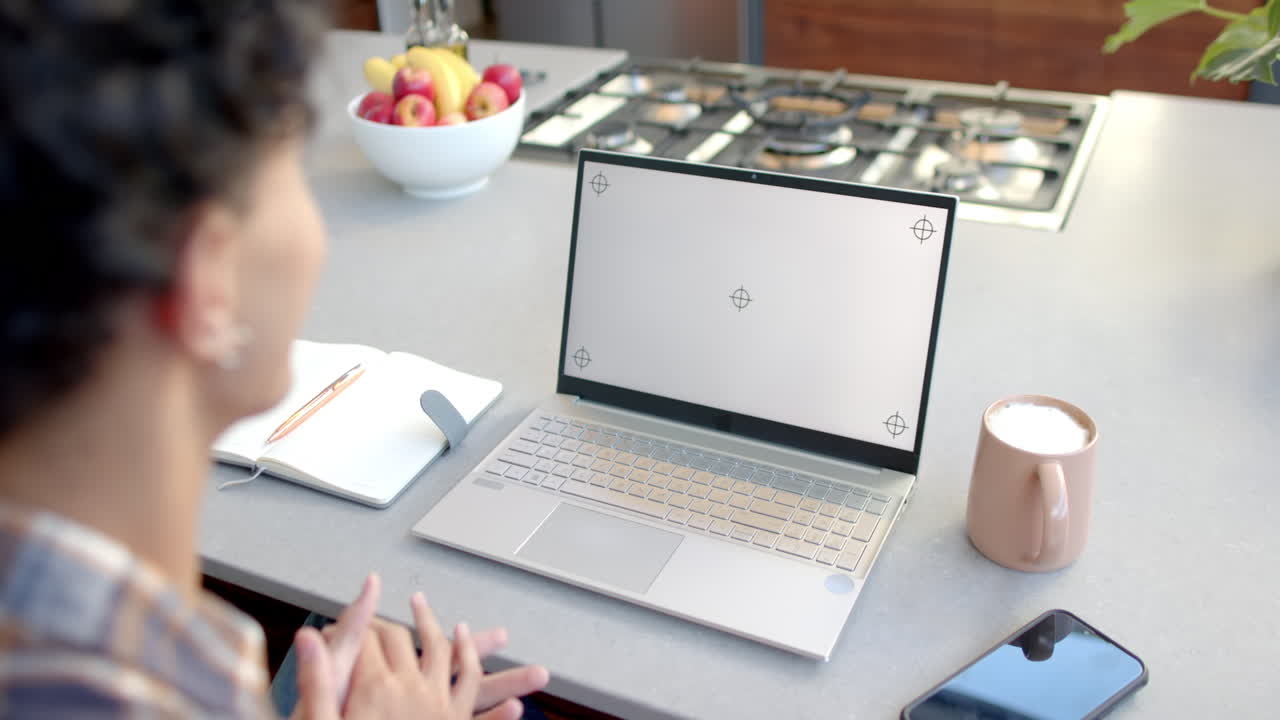 Using laptop on kitchen counter, teenage boy gesturing with notebook and coffee nearby, copy space