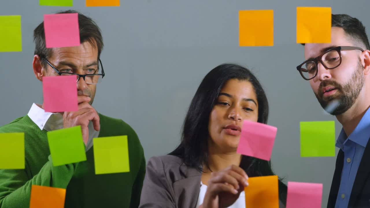 ejecutivos discutiendo sobre una nota adhesiva en la pared de vidrio 4k