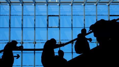 la escalera del aeropuerto de la ventana de vidrio con silueta en movimiento de personas