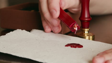 dripping hot wax onto a piece of parchment in preparation for a wax seal