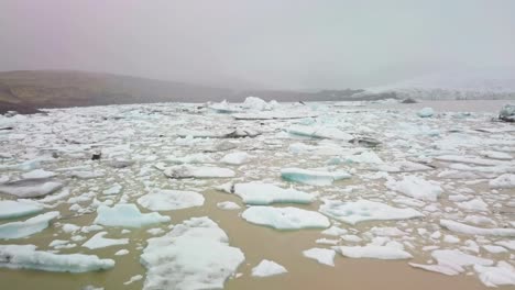 sobre una laguna glaciar llena de icebergs flotantes en un día de niebla en islandia