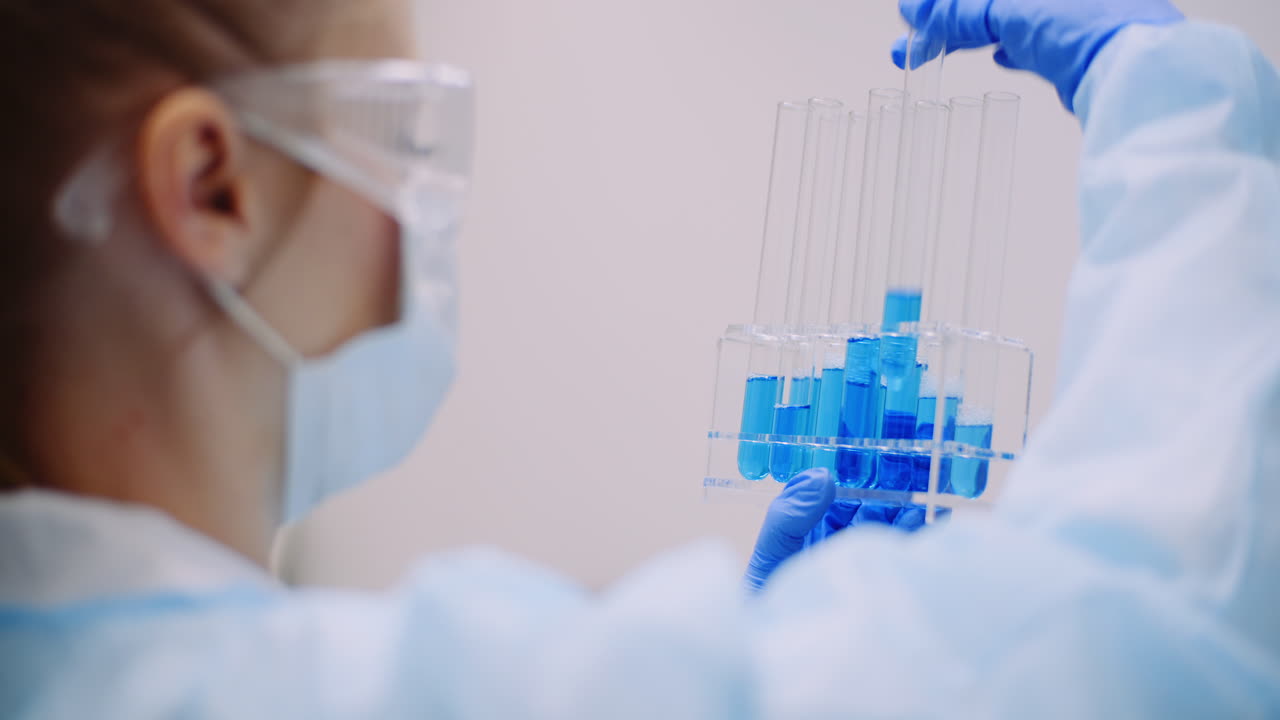 женщина-ученый держит в руках пробирки и колбу с жидкостью 11