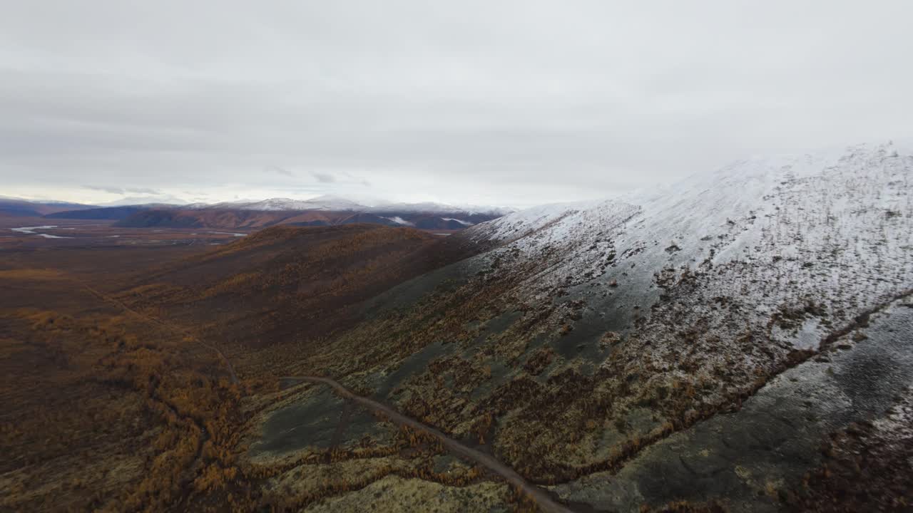 experimenta la impresionante belleza de las altas cadenas montañosas y los vibrantes valles de otoño mientras un dron se desliza con gracia sobre picos nevados y paisajes exuberantes.