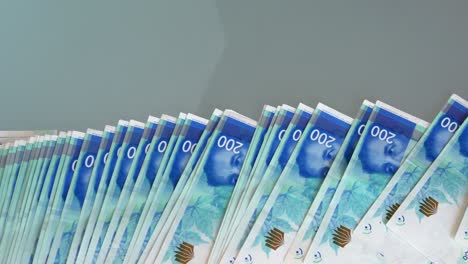 los billetes de papel caen sobre una mesa de vidrio. un primer plano de las finanzas en efectivo israelíes.