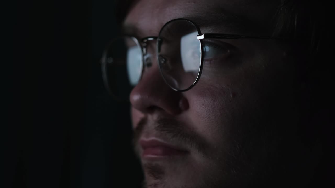 primer plano de un hombre con gafas en la oscuridad