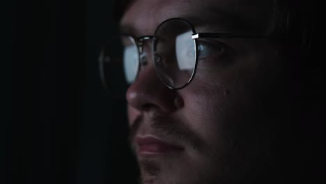 primer plano de un hombre con gafas en la oscuridad