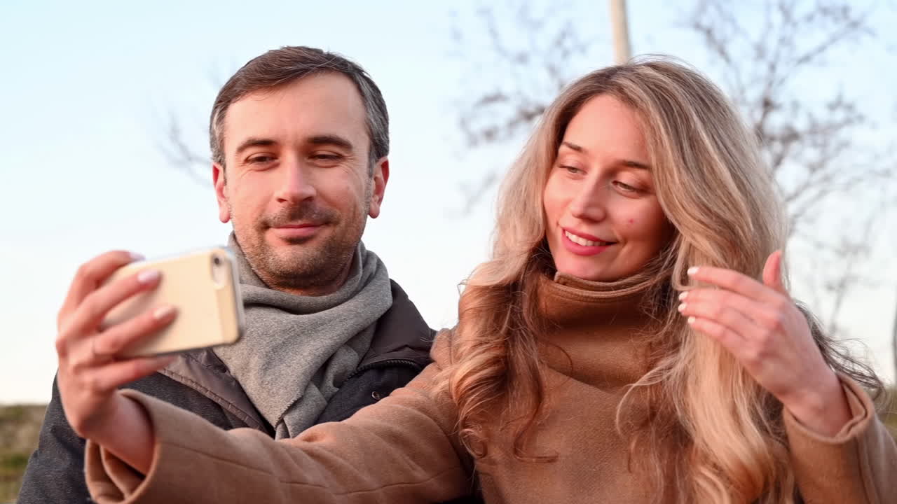 Un giovane uomo e una donna si fanno un selfie in un parco pubblico