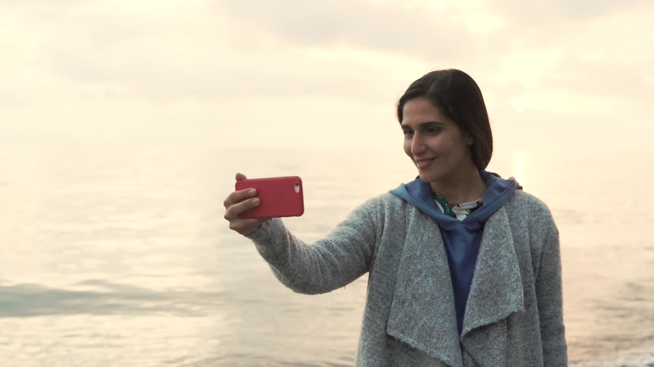 mujer tomando una selfie en la playa al amanecer o al atardecer