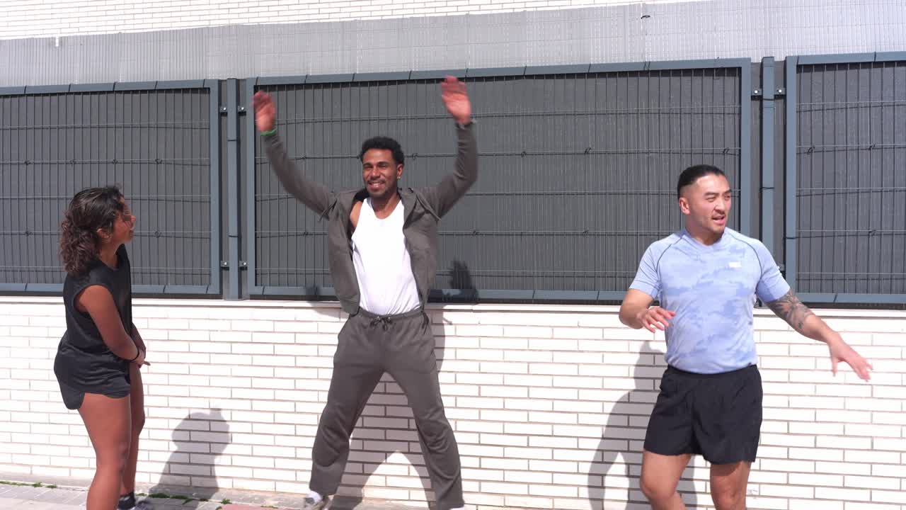 Gruppo eterogeneo di amici che si allenano all'aperto facendo jumping jacks e stretching.