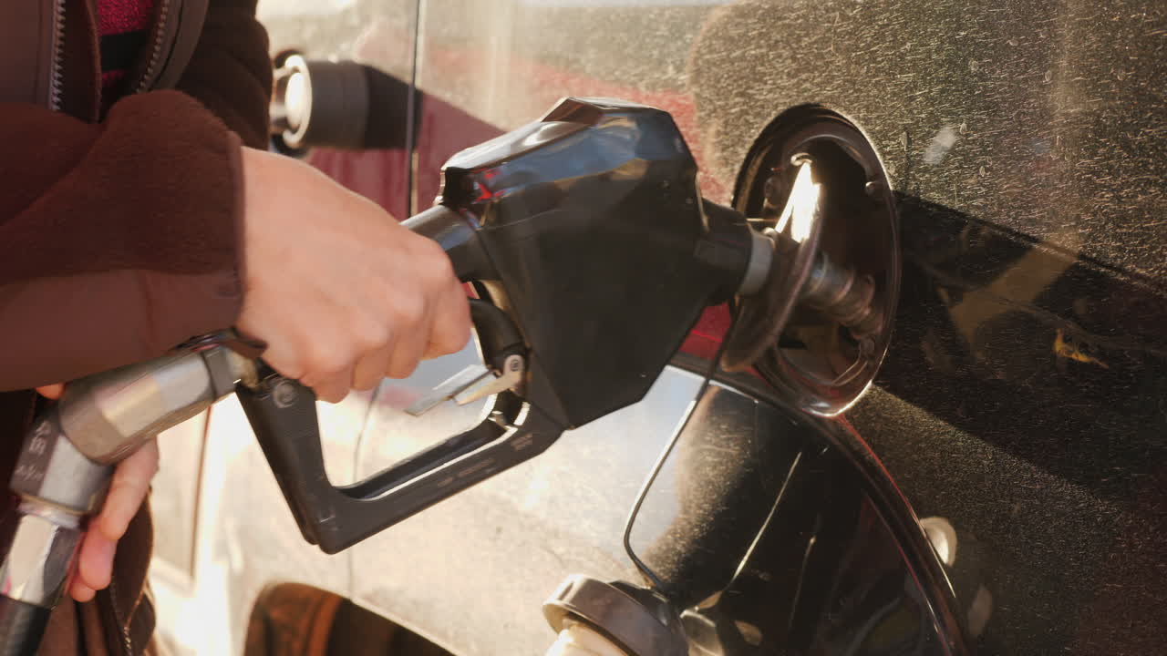 женщина заканчивает закачивать бензин в машину