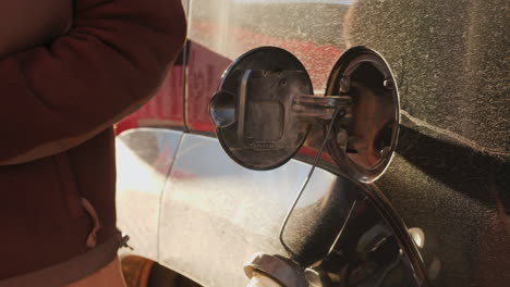 mujer termina de echar gasolina en auto
