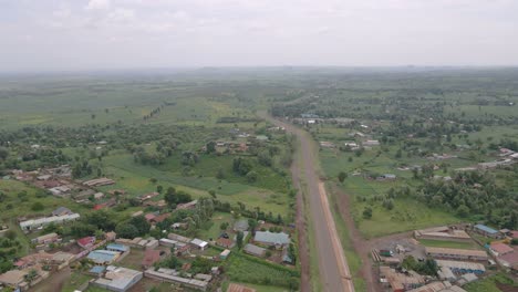 countryside road between green fields and trees in the rural town of loitokitok in kenya - aerial drone shot