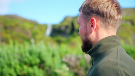 side view of man walking against blurry seljalandsfoss waterfall at background in iceland