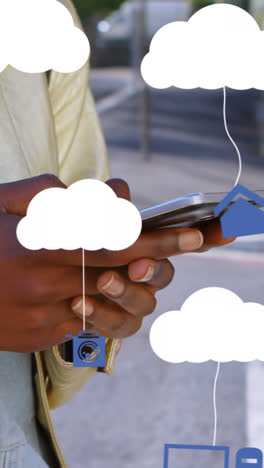 animación de nubes con dispositivos electrónicos sobre una mujer afroamericana que usa un teléfono inteligente