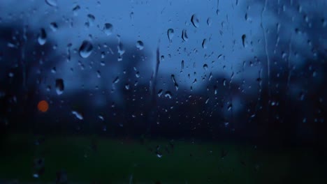rainy storm droplets at night, moody weather fall down window glass closeup bokeh