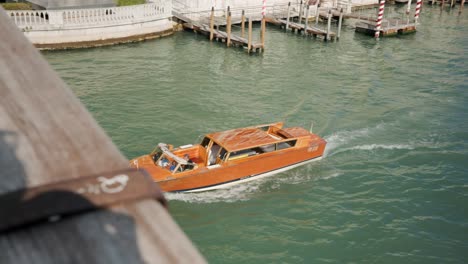 traditional wooden water taxi boat traveling across the grand canal in venice, italy