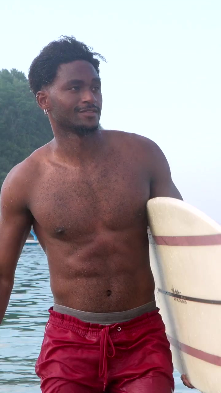 Giovane che esce dall'oceano con una tavola da surf