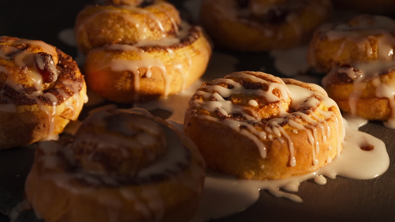 Drizzling Icing On Top Of Cinnamon Rolls. - closeup shot