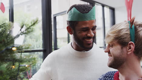 Gay-Male-Couple-At-Home-Hanging-Decorations-On-Christmas-Tree-Together