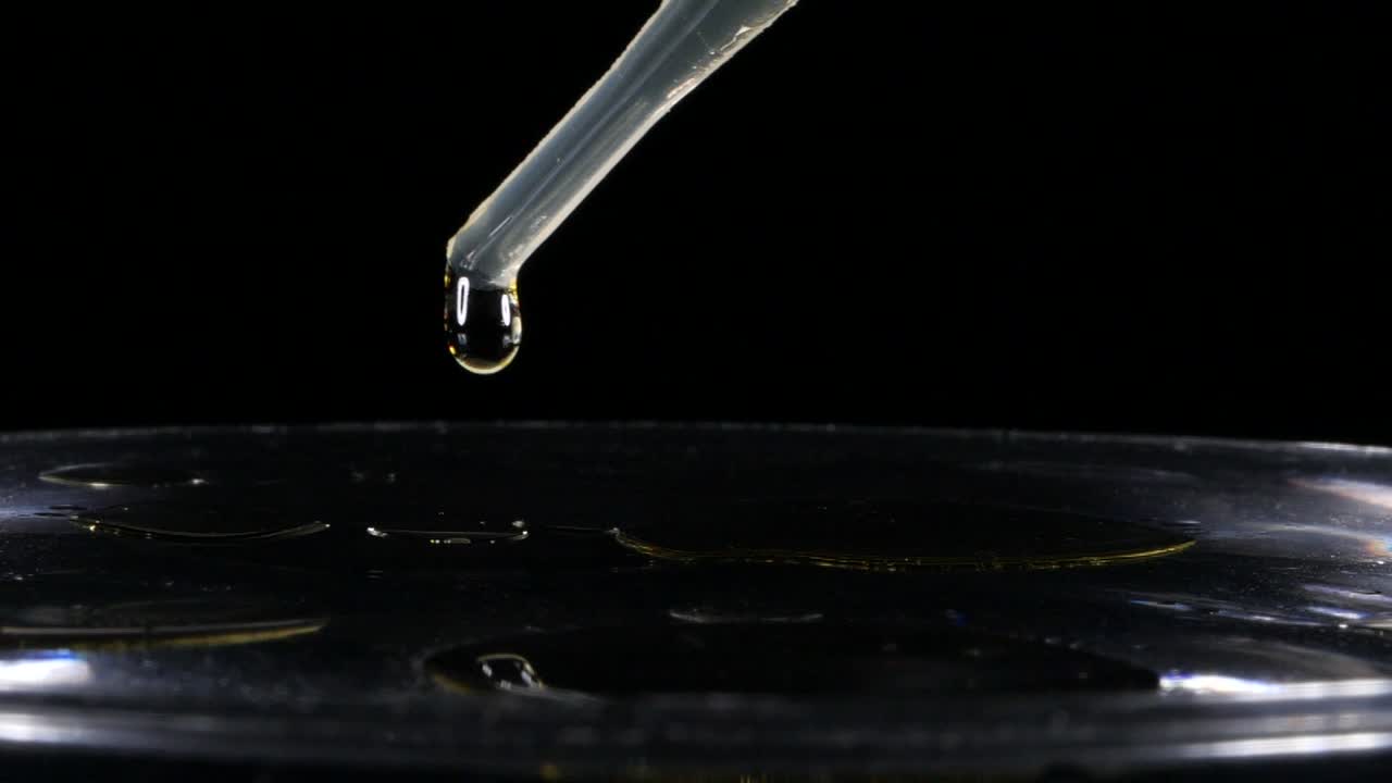 맑은 물에 향유를 바르고 검은색 배경을 닫습니다.