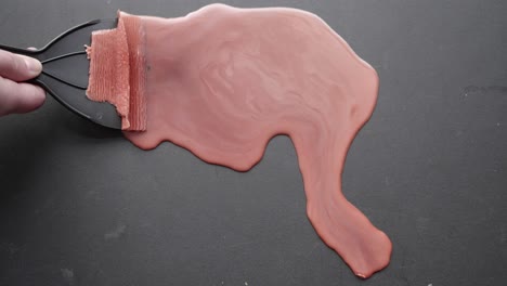 cera roja siendo satisfactoriamente raspada de una superficie negra