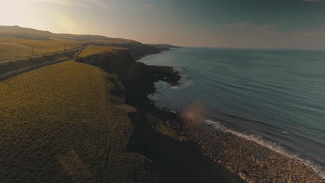 berwick-upon-tweed in scotland - drone capturing a coastal cliff with green landscape surrounded by tranquil waters at sunset - aerial drone shot