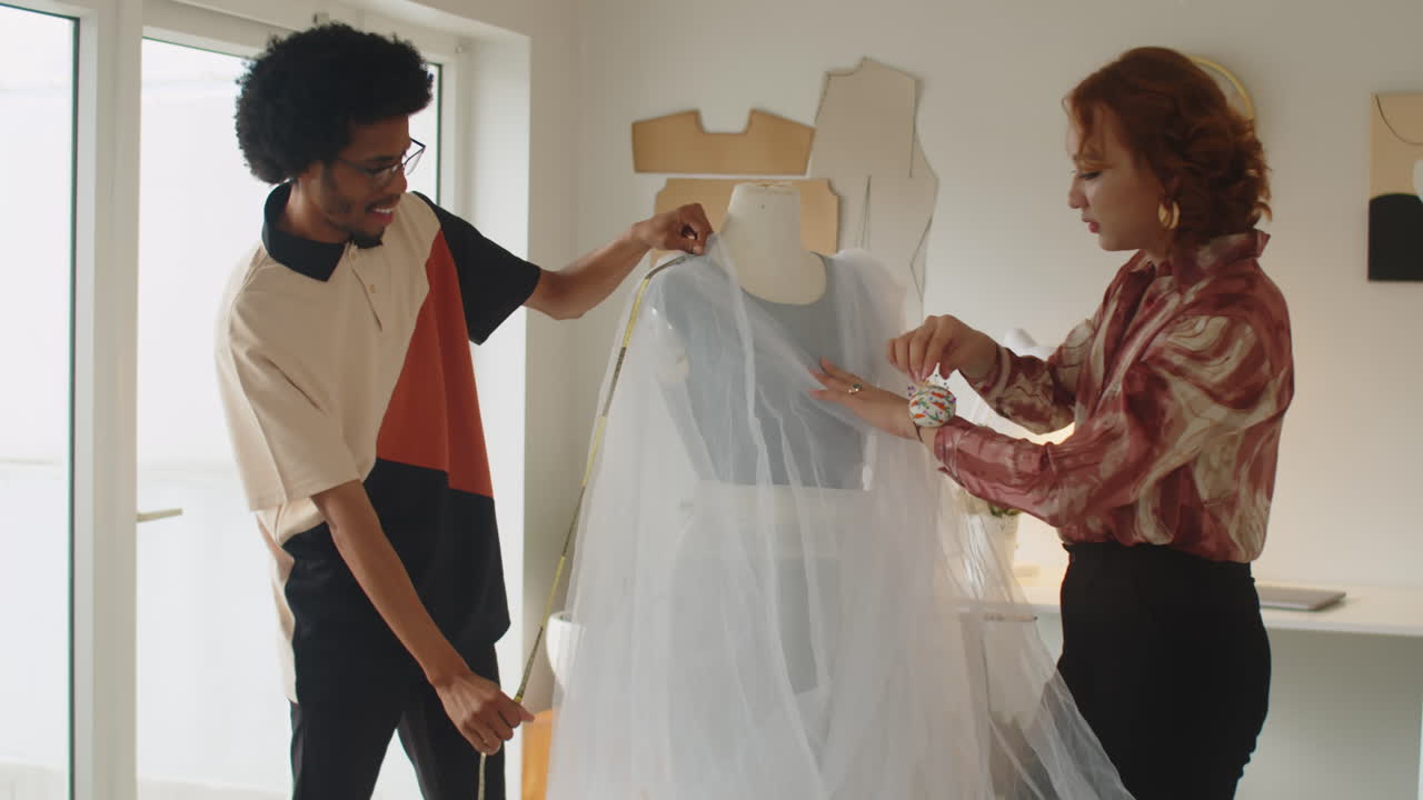 Two Tailors Measuring Wedding Dress on Mannequin