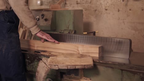 close up footage of man in work clothes working on electric saw with wooden material in carpentry. slow motion