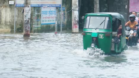 bangladesh submerged city street during flood crisis. public vehicles traveling through