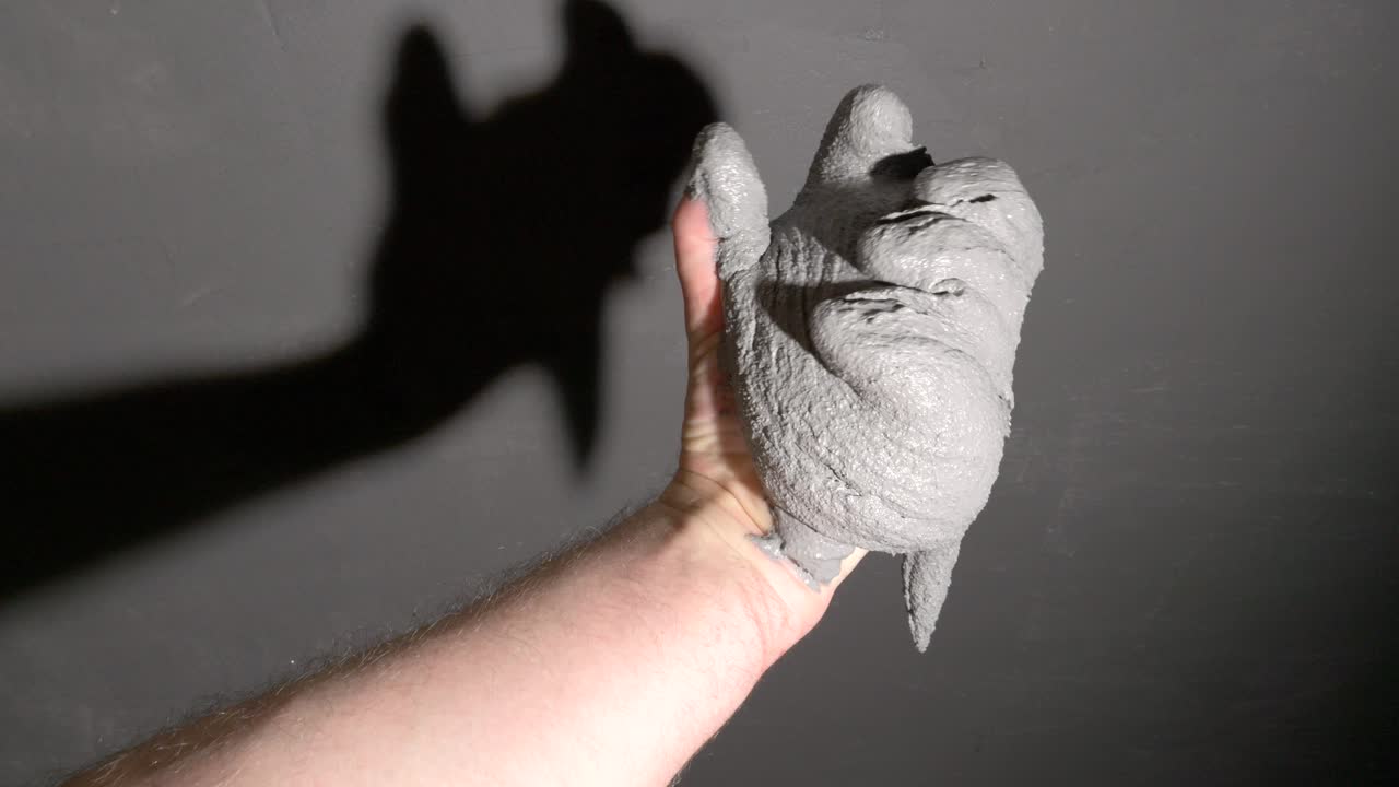 회색 벽에 대한 장식 플라스터로  ⁇ 인 더러운 손이 나타납니다.