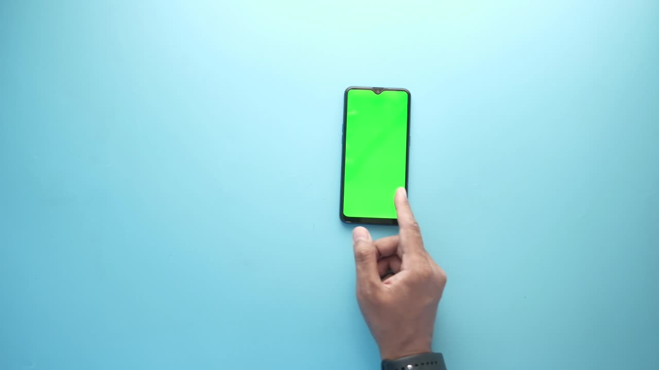 파란색 배경에 스마트 폰을 사용하는 사람의 손의 상단 뷰