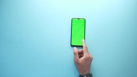 vista superior de la mano del hombre usando un teléfono inteligente sobre un fondo azul