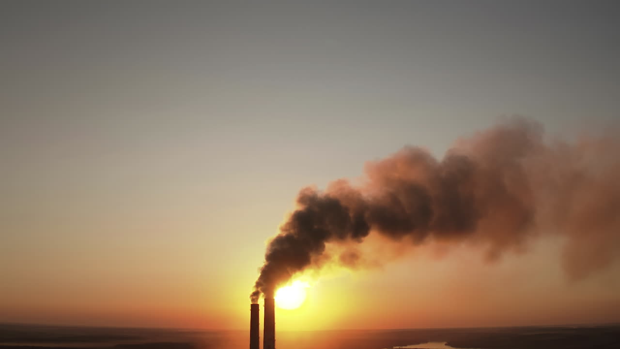 Toxic dark smoke filling the evening sky. Pipes with chemical emissions going into the air against the sunset. Ecological problems in the atmosphere.