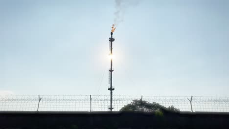 Flare-pit-gas-combustion-refinery-behind-wired-fence,-static,-close-up,-day
