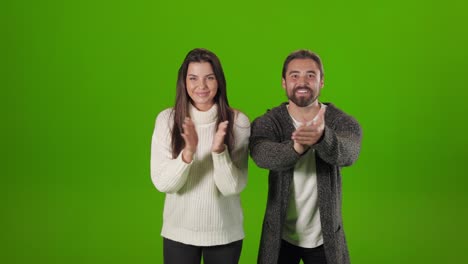 pareja aplaudiendo alegremente en el estudio con fondo verde