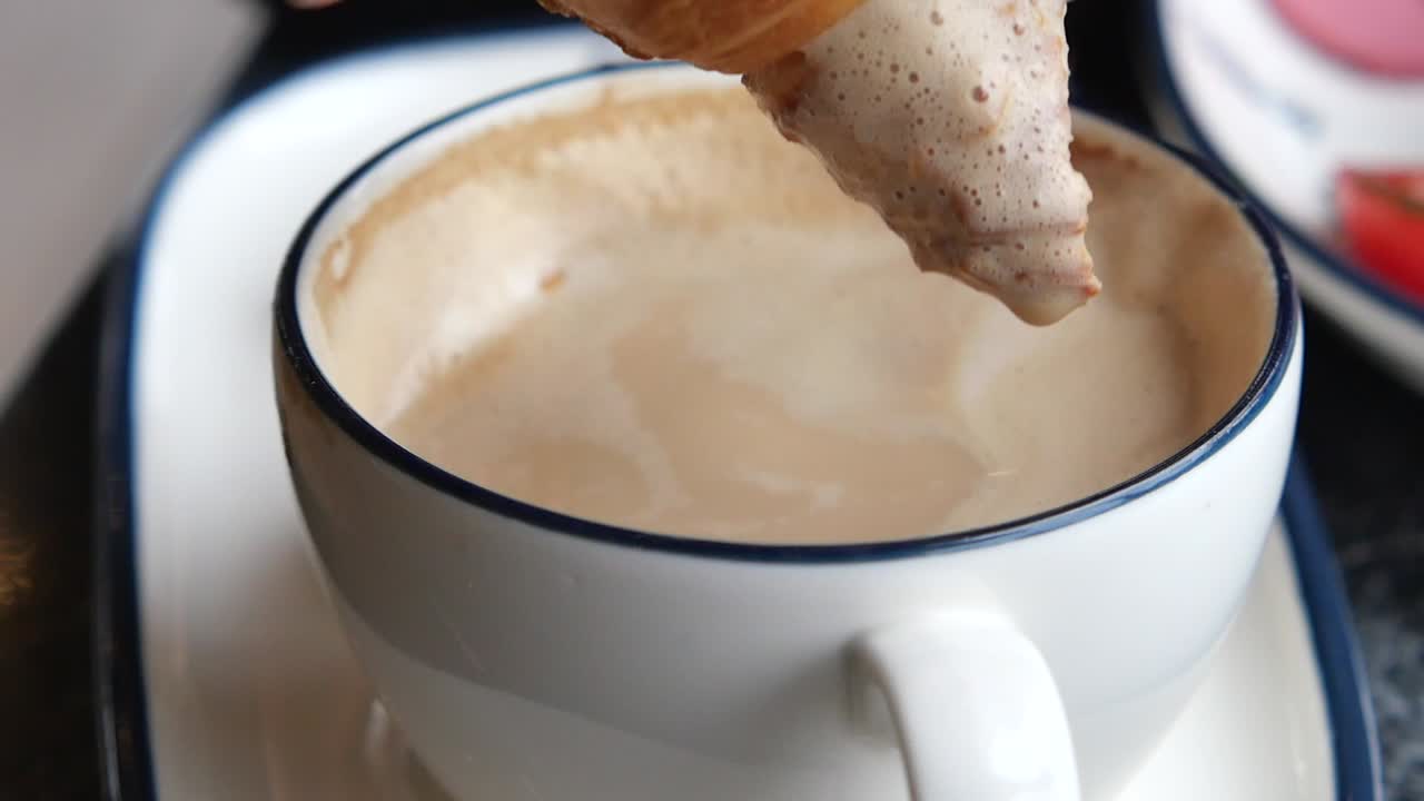 Croissant being dipped in coffee