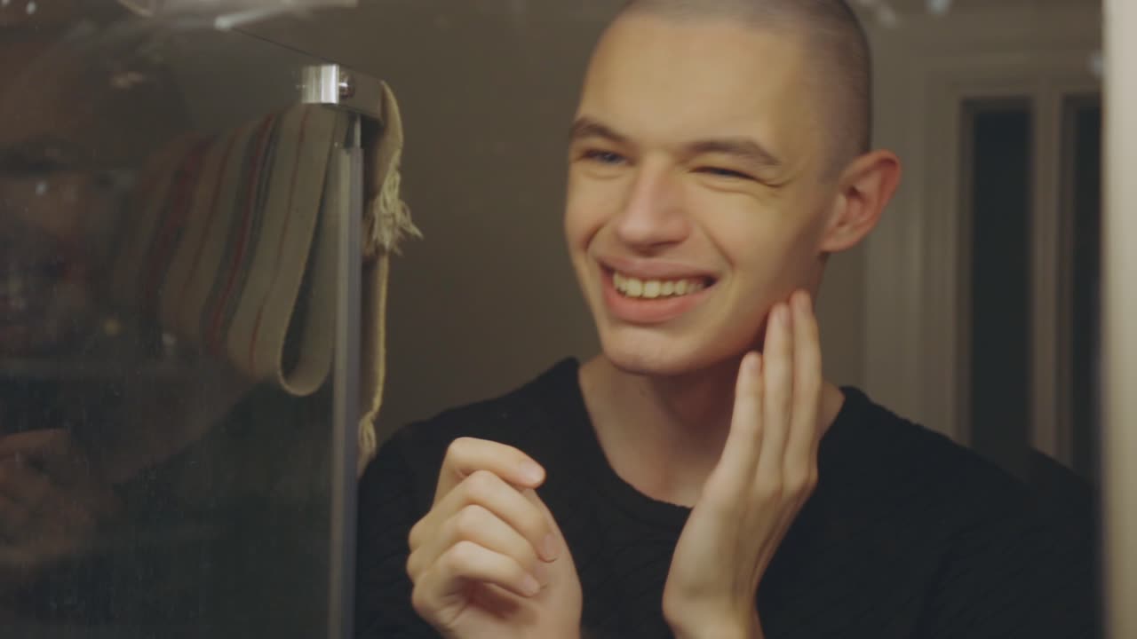 Handsome Young Man Looking In Front Of Mirror Touching His Newly Shaved Face - Closeup Shot