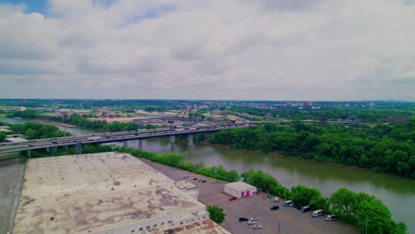 wide drone view of nashville, tn showcasing an interstate bridge crossing the cumberland river, dense greenery, and surrounding development