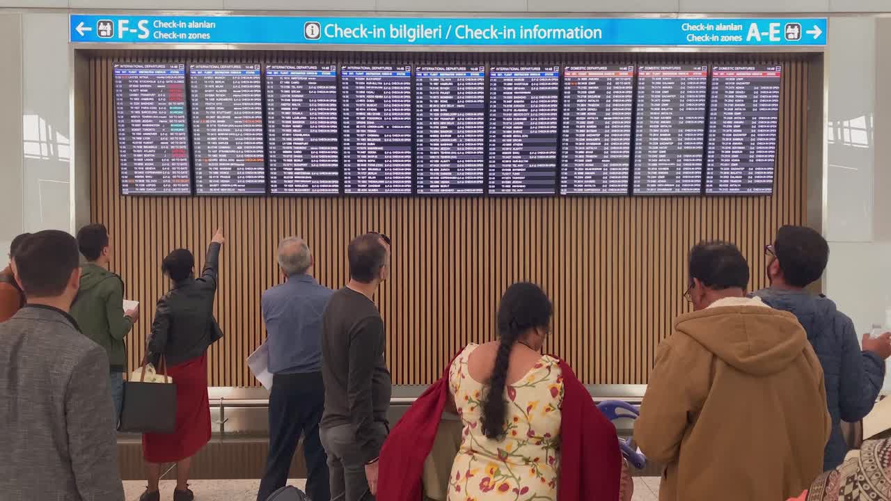 People are watching at the check-in board at the Istambul Havalimani International airport
