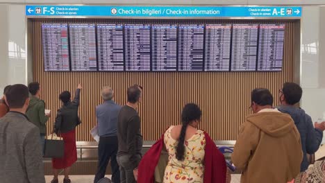 people are watching at the check-in board at the istambul havalimani international airport