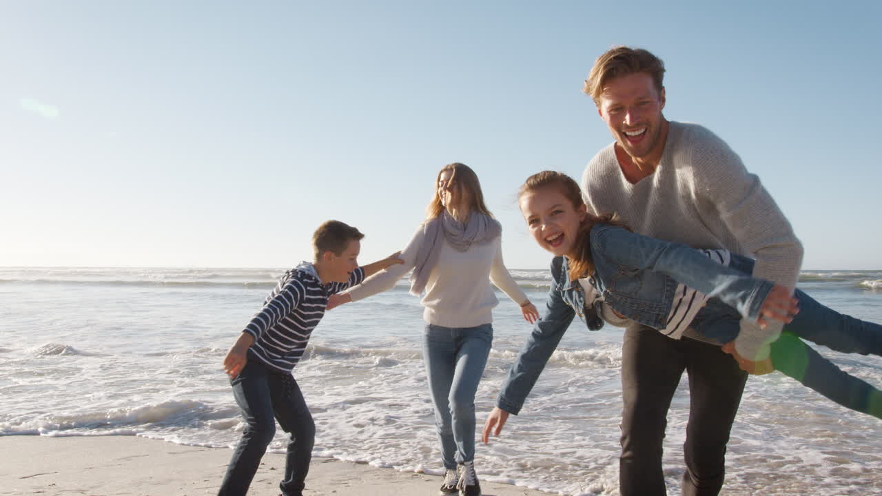 familia en la playa de invierno huyendo de las olas que avanzan