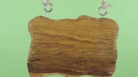 zoom of an old wooden sign hanging on a rope. information old board on the isolated green background