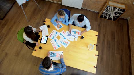reunión de negocios en el loft espacio compartido. equipo hablando, mujer gerente dando dirección a la gente. vista superior.