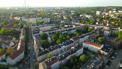 vuelo aéreo sobre los tejados de la ciudad de gdansk y calles limpias con autos estacionados cerca de los edificios puesta de sol desde un punto de vista alto, espacio de copia