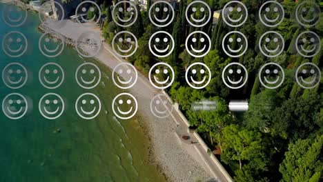 Digital-composition-of-rows-of-multiple-smiling-face-emojis-against-aerial-view-of-the-beach