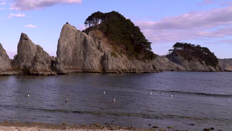 Slow-tilt-up-over-beautiful-jagged-rock-cliffs-and-seagulls-in-ocean