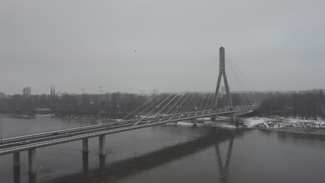 Drone-video-of-and-swietokrzsyki-bridge,-warsaw-above-Vistula-river-on-a-snowy-day