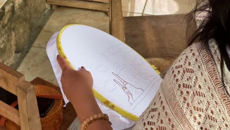 la mano de la mujer está encerando el dibujo en textil para hacer batik