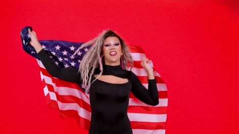 A drag queen holds an American flag against a red background